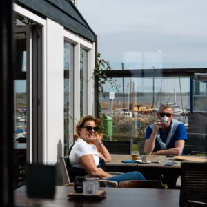 Gasten genieten in de zon op het terras van Het Raadsel van de Wadden in Oostmahorn Friesland