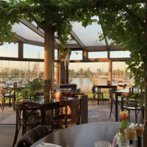 Serre van restaurant Lauwersmeer Het Raadsel van de Wadden in Oostmahorn Friesland met druivenstruik en uitzicht op het Lauwersmeer en de jachthaven