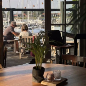 Stel geniet op het terras van restaurant Lauwersmeer Het Raadsel van de Wadden van het uitzicht en het mooie weer in Oostmahorn Friesland