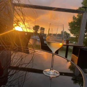 Witte wijn bij zonsondergang op het terras van restaurant Lauwersmeer Het Raadsel van de Wadden in Oostmahorn Friesland.